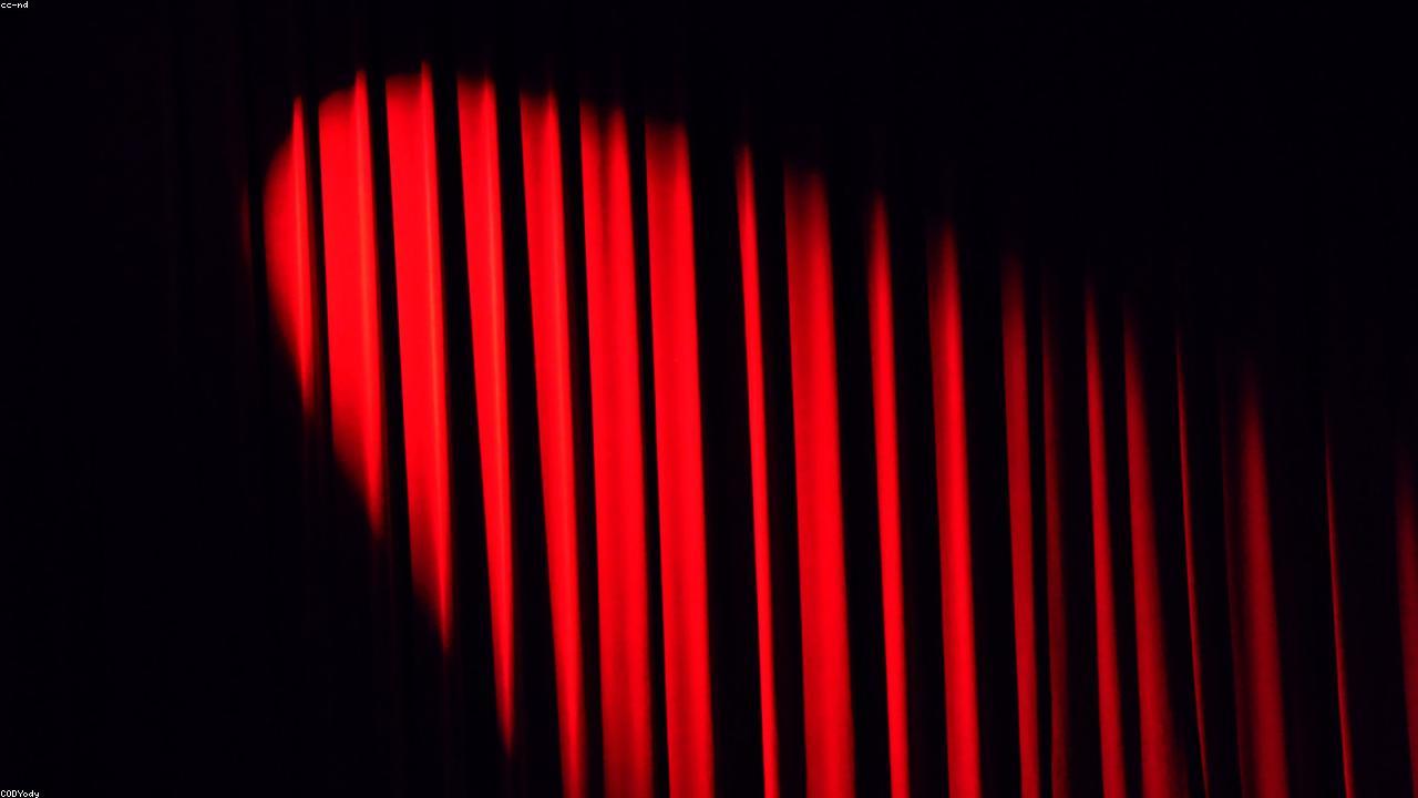 Empty theatre with classical proscenium and red velvet curtain.